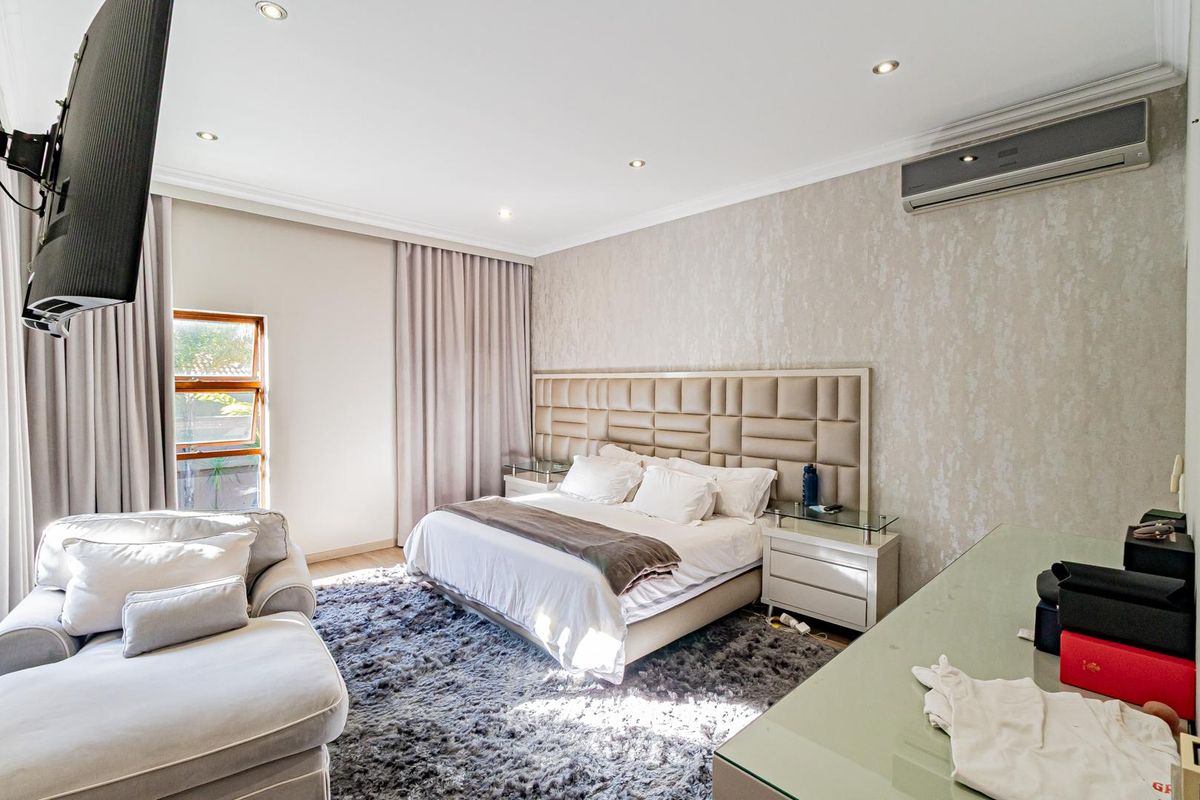 A well-maintained bedroom featuring recessed downlighting, a wall-mounted air conditioning unit, and decorative textured wallpaper.