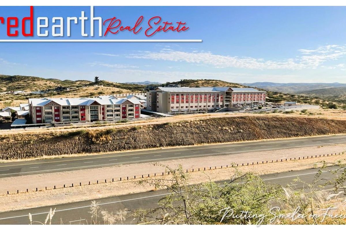 An elevated aerial view of the retirement village complex, showcasing the multi-story residential buildings set within a scenic, arid landscape.