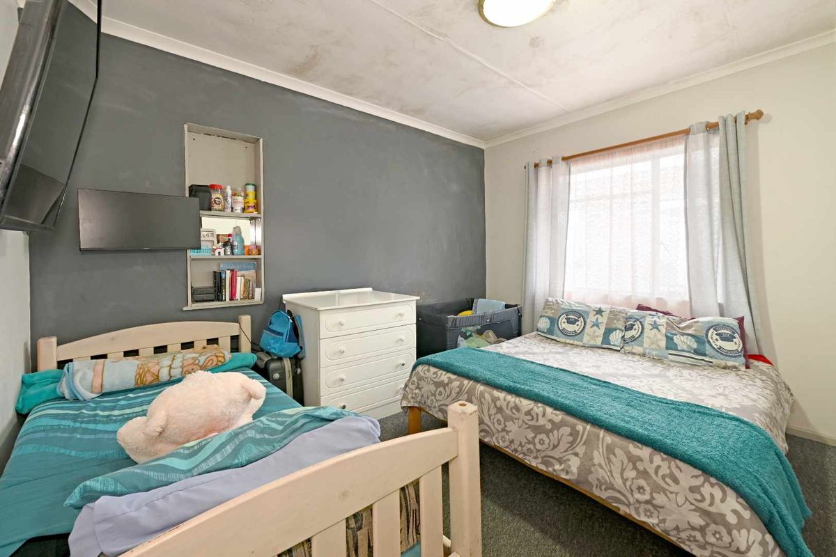 A bedroom featuring a built-in wall niche, carpeted flooring, and a window with curtain rod.