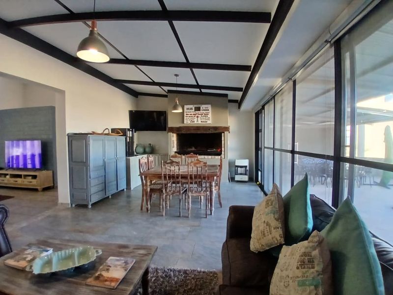 Spacious open-plan living and dining area featuring exposed ceiling beams, a built-in fireplace, and large glass sliding doors leading to the patio.