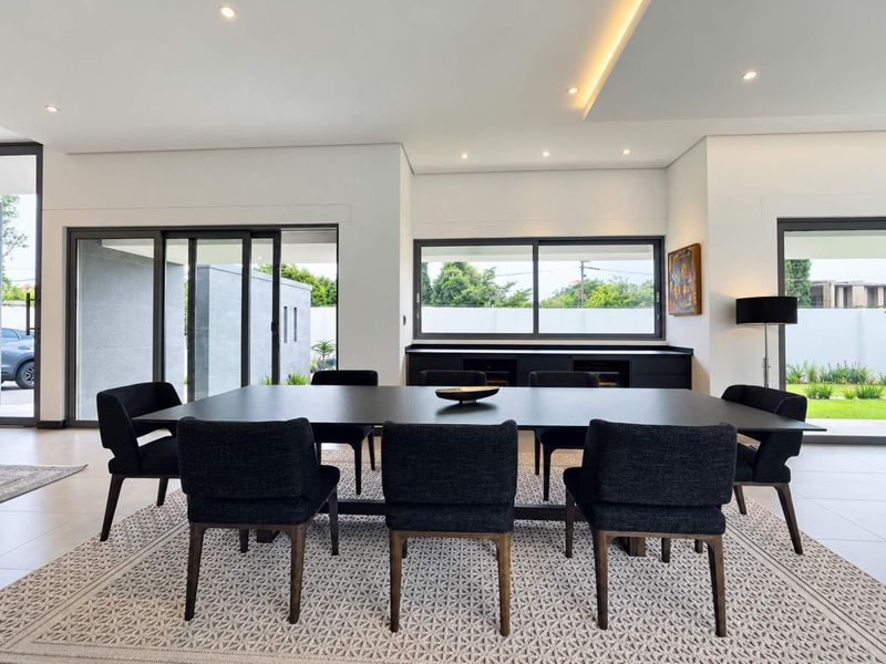 Modern dining room featuring sleek built-in cabinetry, recessed ceiling lighting, and large sliding glass doors that provide seamless access to the outdoor area.