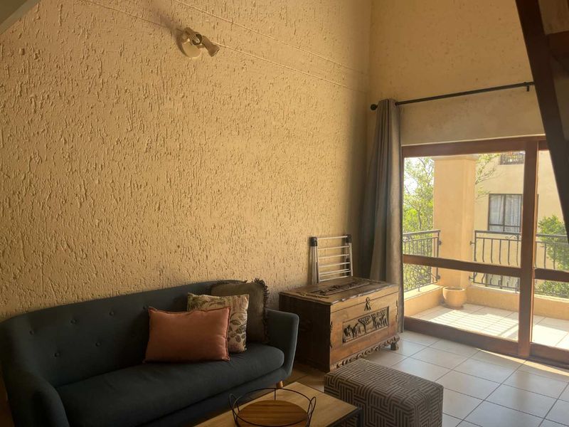 Living room featuring tiled flooring, textured walls, and a sliding glass door providing direct access to an outdoor balcony area.