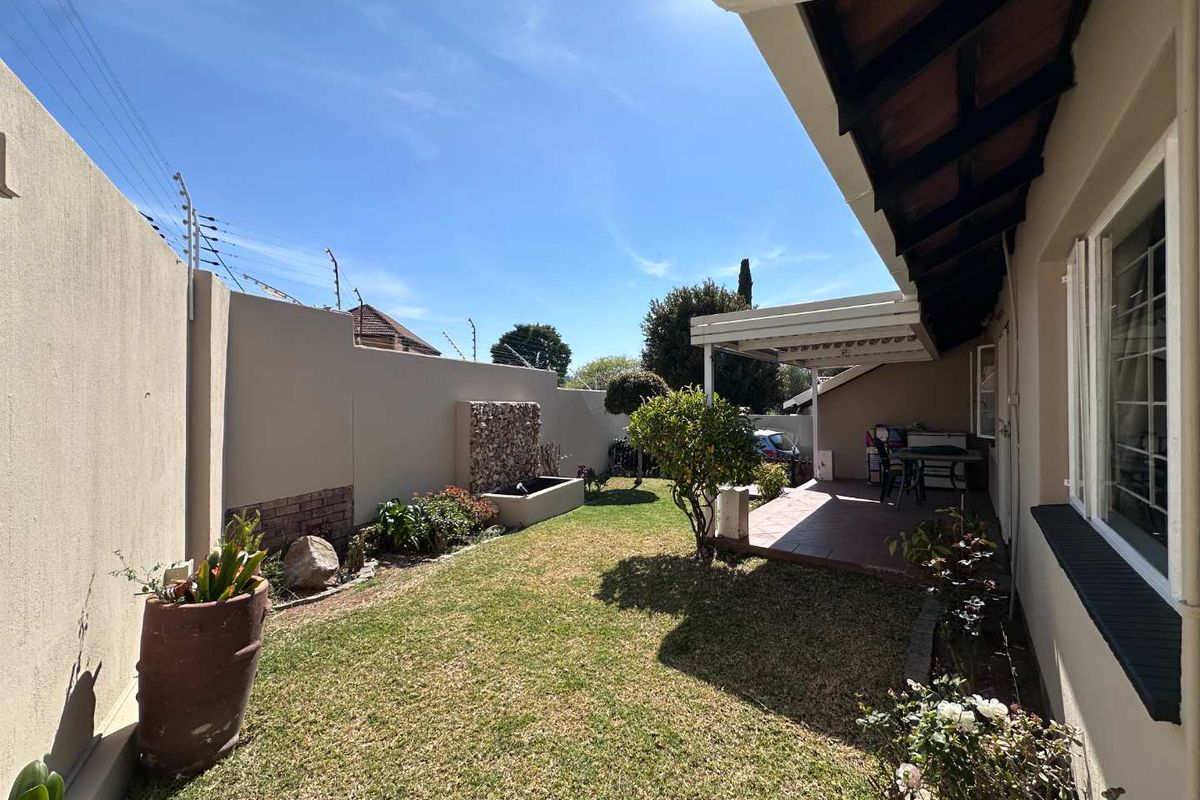 A private rear garden featuring a covered patio, a built-in water feature, and secure boundary walls with electric fencing.