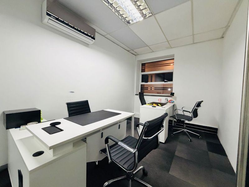 A functional office space featuring a suspended ceiling, recessed lighting, split-system air conditioning, and carpet tile flooring.