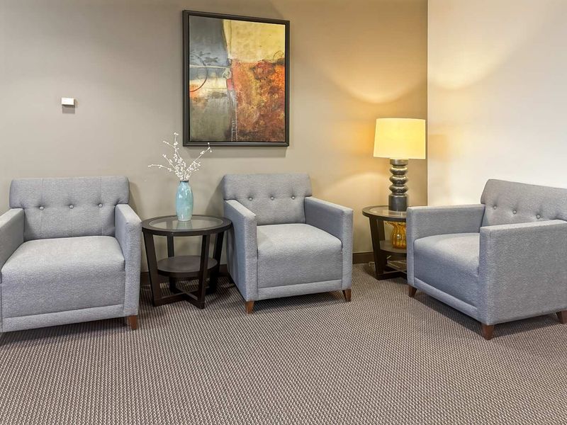 A professional office waiting area featuring neutral wall tones and carpeted flooring.