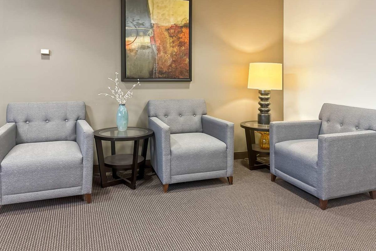 A professional office waiting area featuring neutral wall tones and carpeted flooring.
