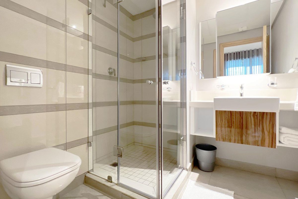 Modern bathroom featuring a glass-enclosed shower, wall-mounted toilet with concealed cistern, and a floating vanity with integrated basin.