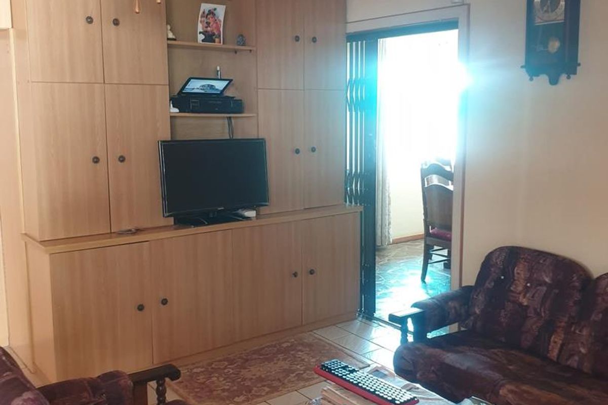 A living room featuring built-in wooden cabinetry, tiled flooring, and a ceiling fan, with a doorway leading to an adjacent space.