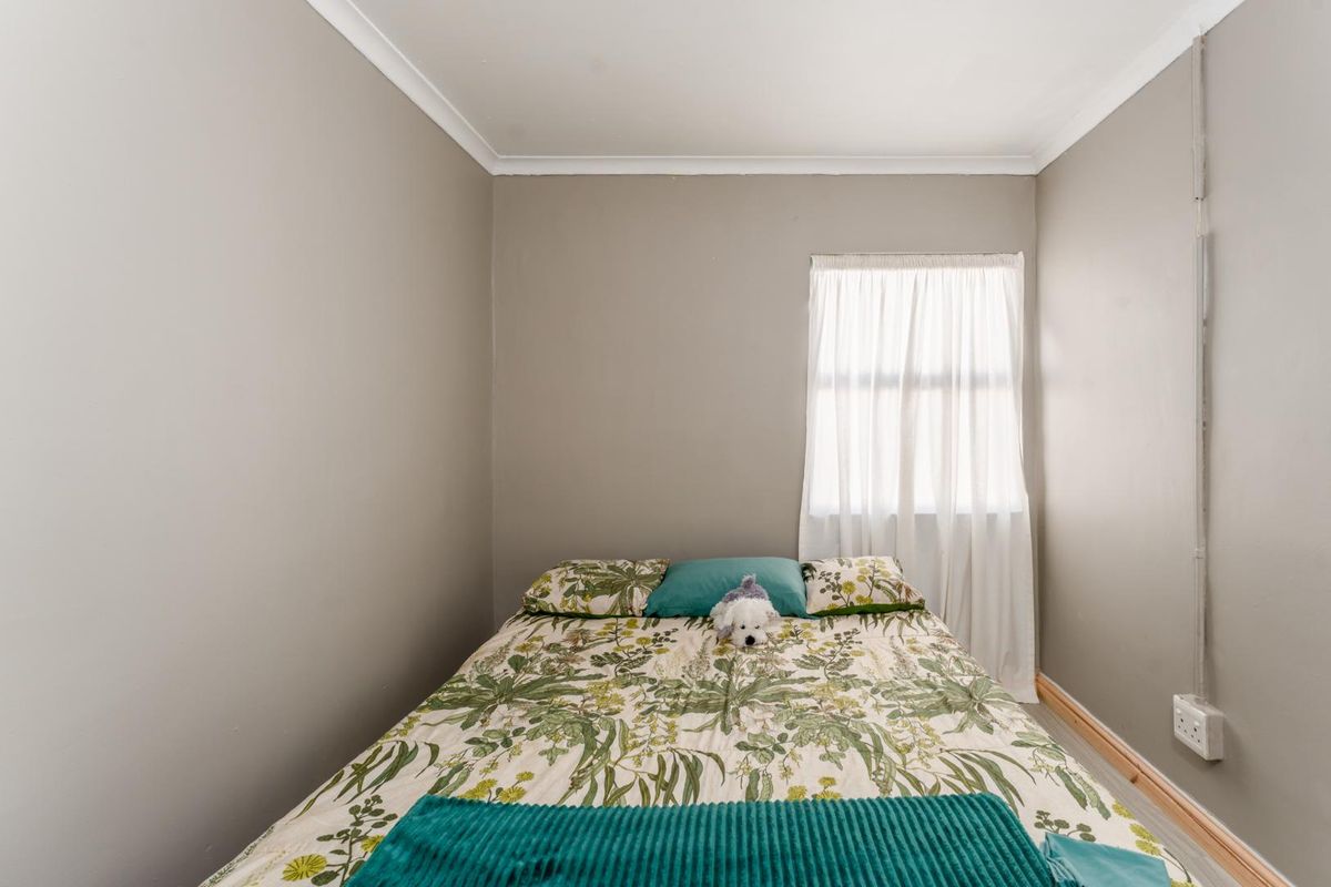 A compact bedroom featuring neutral wall tones, coved ceiling cornicing, and a single window with natural light.