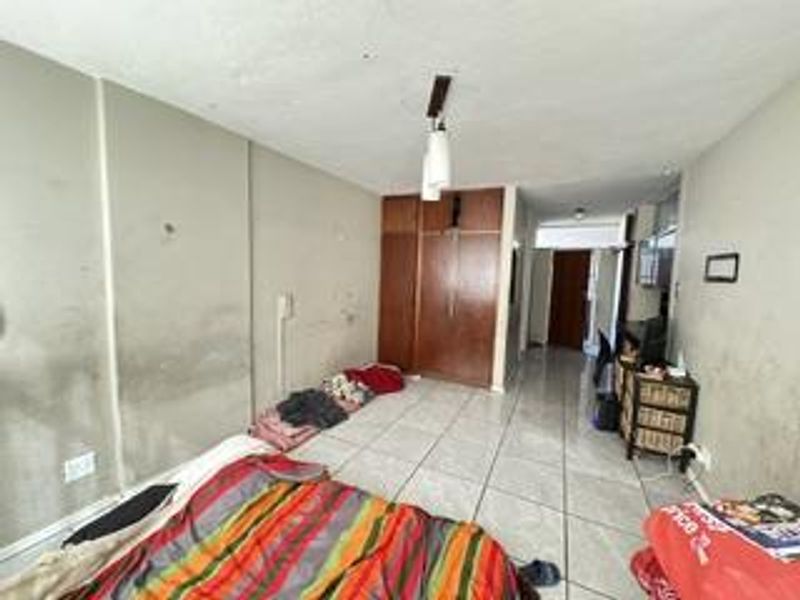 Bedroom featuring tiled flooring and built-in wooden cupboards, requiring cosmetic attention to wall finishes.