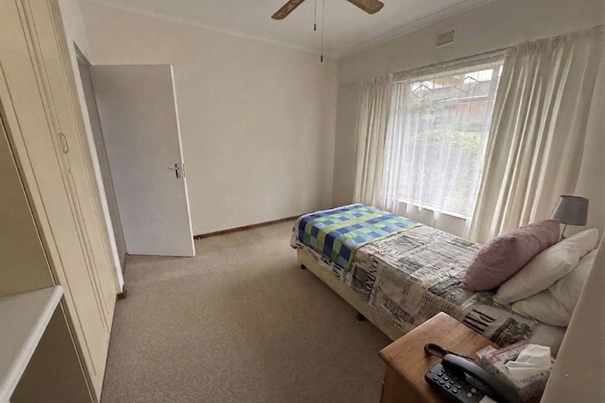 A functional bedroom featuring built-in cupboards, a ceiling fan, and neutral carpeting, offering a comfortable and practical living space.