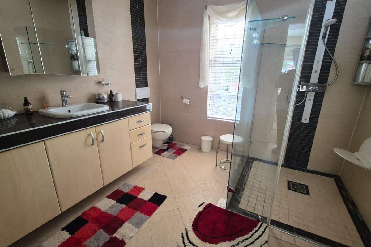 A functional bathroom featuring a vanity with a countertop basin, a walk-in glass shower enclosure, and tiled flooring.