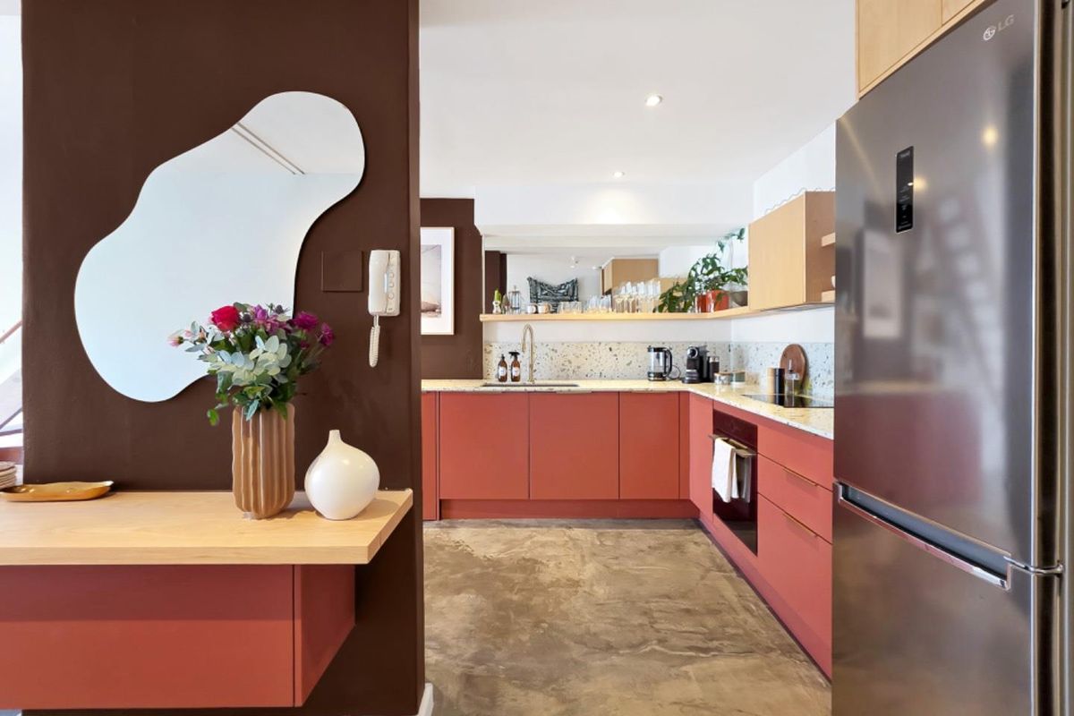 Modern kitchen featuring terracotta-toned cabinetry, terrazzo countertops, polished concrete flooring, and integrated appliances, creating a stylish and functional culinary space.