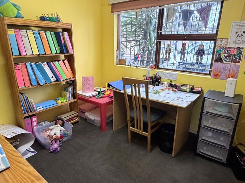 A functional home office space featuring a window with security bars and roller blinds, currently utilized as a study area.