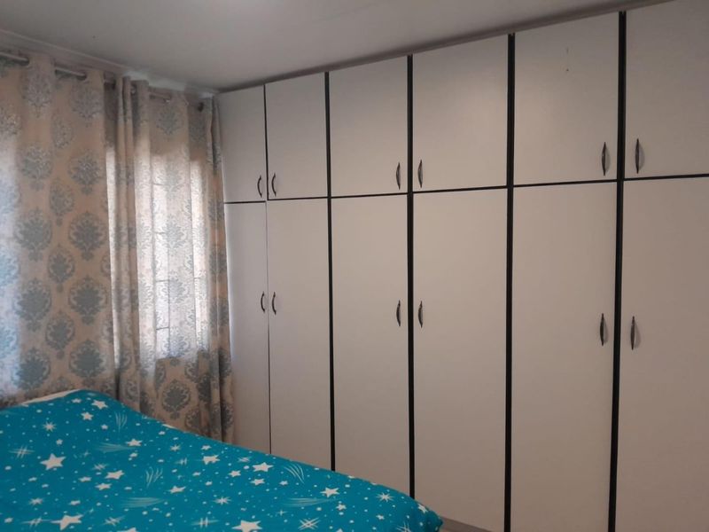 A bedroom featuring extensive floor-to-ceiling built-in cupboards providing ample storage space.