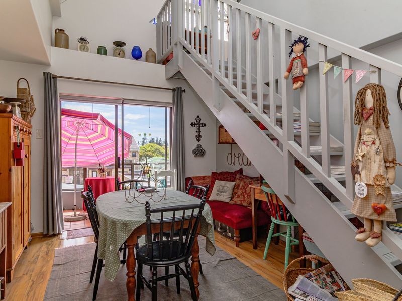 Open-plan living area featuring a staircase leading to a mezzanine level and sliding glass doors providing access to an outdoor balcony.