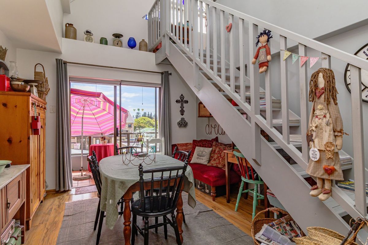Open-plan living area featuring a staircase leading to a mezzanine level and sliding glass doors providing access to an outdoor balcony.