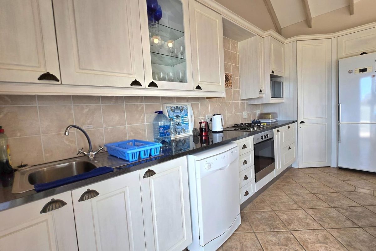A functional kitchen featuring white cabinetry, dark countertops, tiled backsplash, built-in oven, gas hob, and tiled flooring.