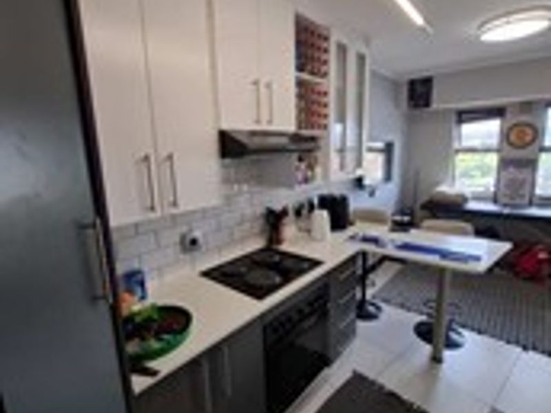 Modern kitchen featuring two-tone cabinetry, stone countertops, subway tile backsplash, integrated hob and oven, and a convenient breakfast bar area.