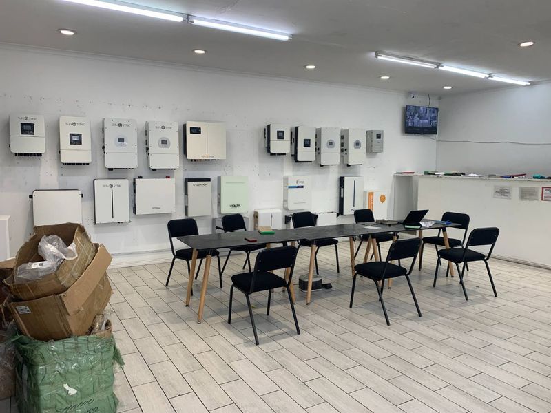 A utility or showroom space featuring multiple wall-mounted solar inverters, tiled flooring, and functional overhead lighting.
