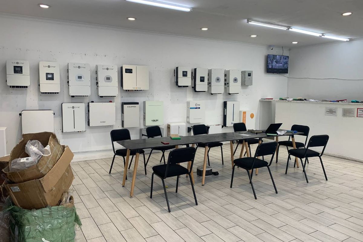 A utility or showroom space featuring multiple wall-mounted solar inverters, tiled flooring, and functional overhead lighting.
