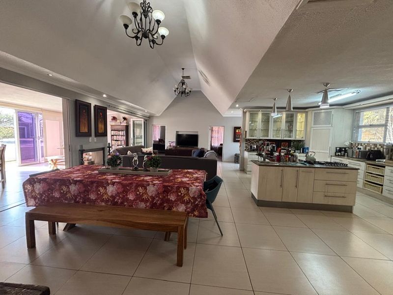 Spacious open-plan living area featuring a vaulted ceiling, tiled floors, and a modern kitchen with a central island and integrated appliances.