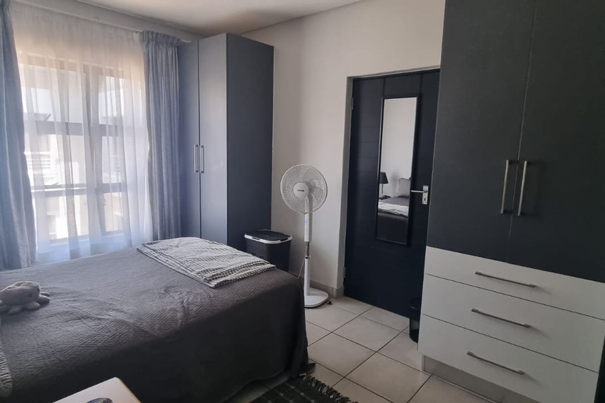 A well-maintained bedroom featuring built-in cupboards with a modern two-tone finish and tiled flooring.