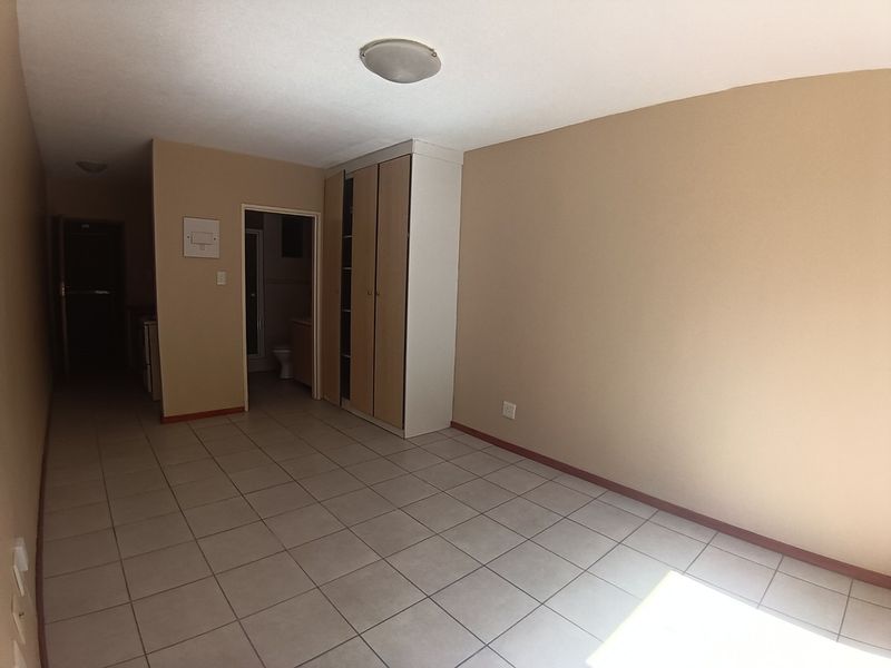 An empty bedroom featuring tiled flooring and built-in cupboards, with direct access to an en-suite bathroom.