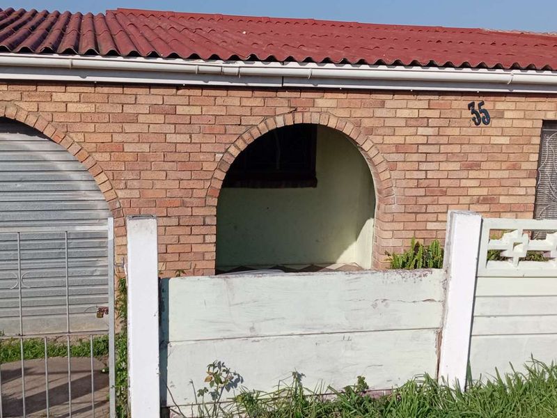 Front elevation of a single-story brick house featuring an arched entrance, roller shutter garage door, and a precast concrete boundary wall.