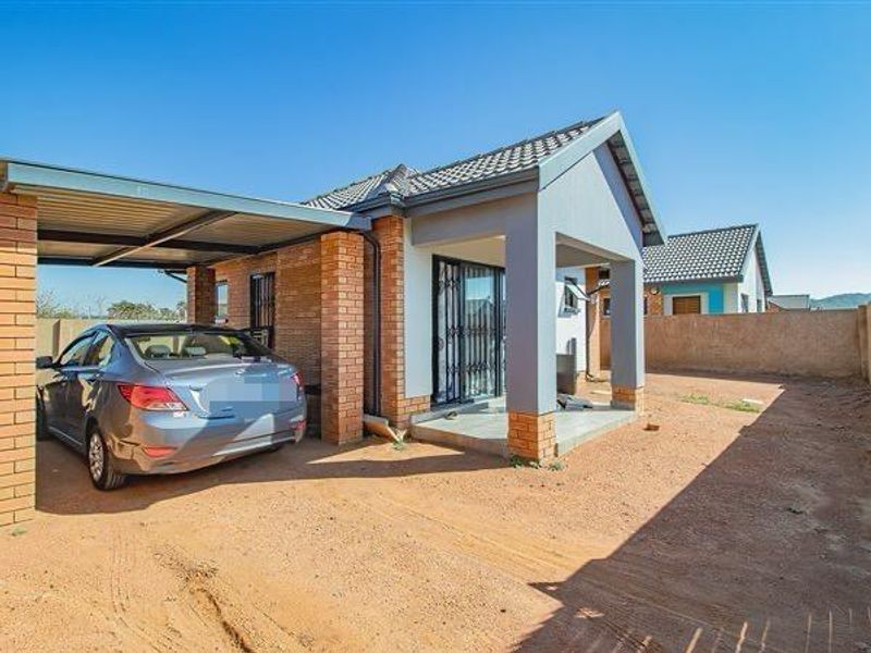 Front exterior view of a modern brick house featuring a covered carport, tiled roof, and secure sliding door entrance with an unpaved yard area.