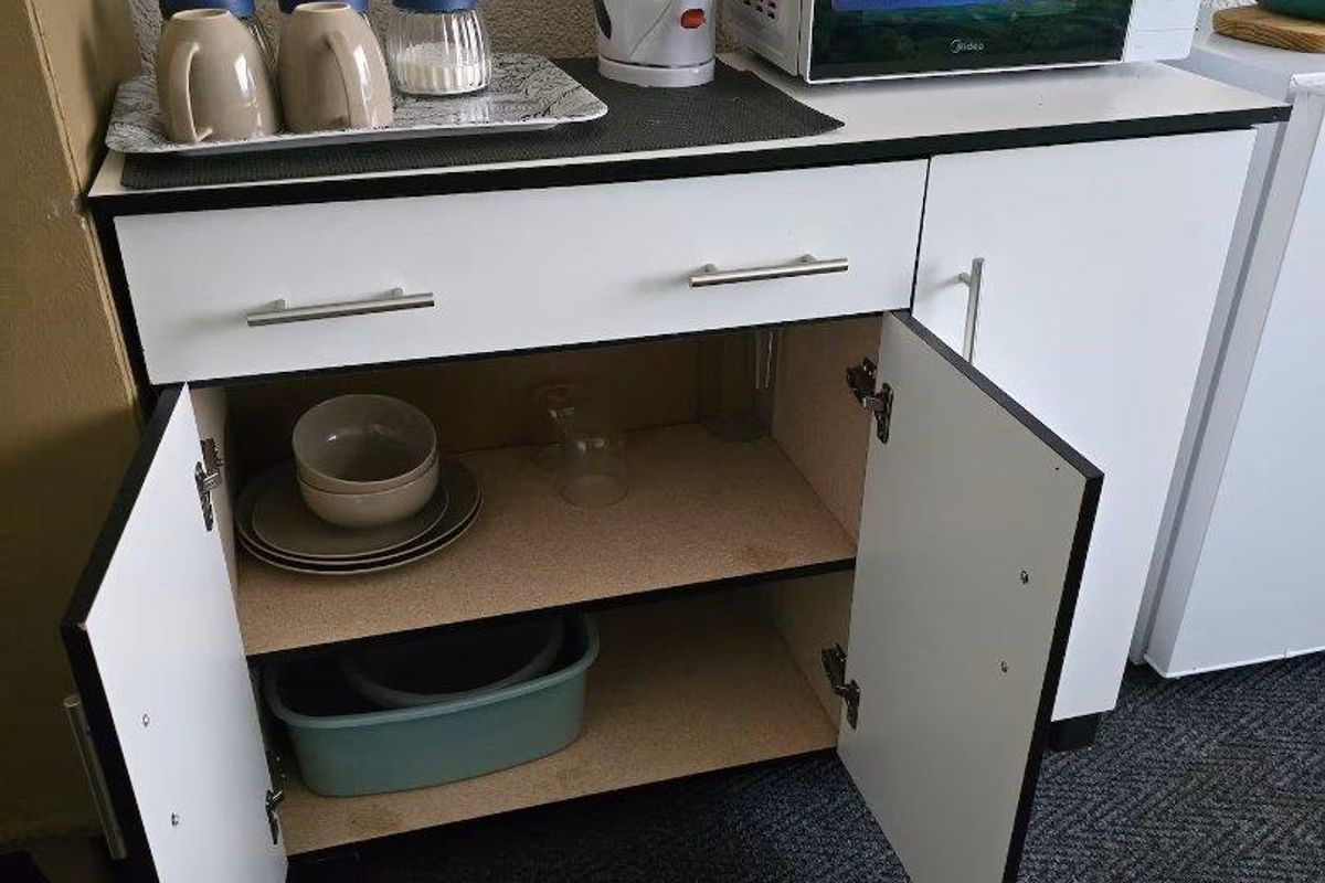 A compact kitchen cabinet unit featuring white doors, a drawer, and a countertop, providing functional storage and surface space for small appliances.