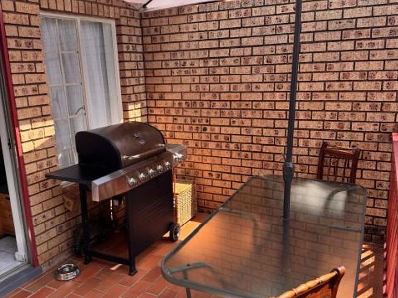 A private outdoor patio area featuring exposed brick walls and terracotta tile flooring, suitable for outdoor dining and relaxation.