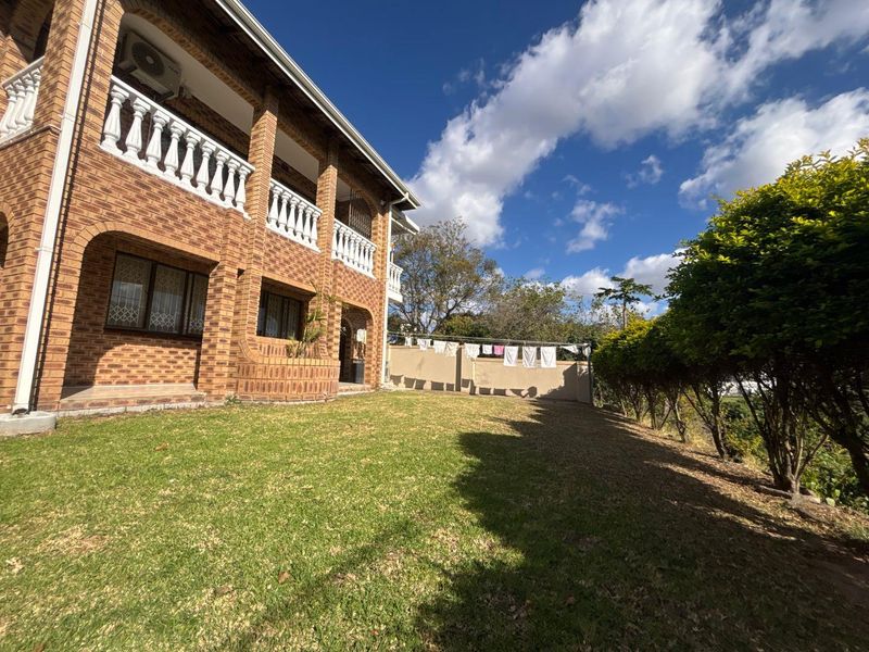 A view of the rear exterior of the cottage, featuring a face brick facade, upper-level balustrades, and a well-maintained lawn area.