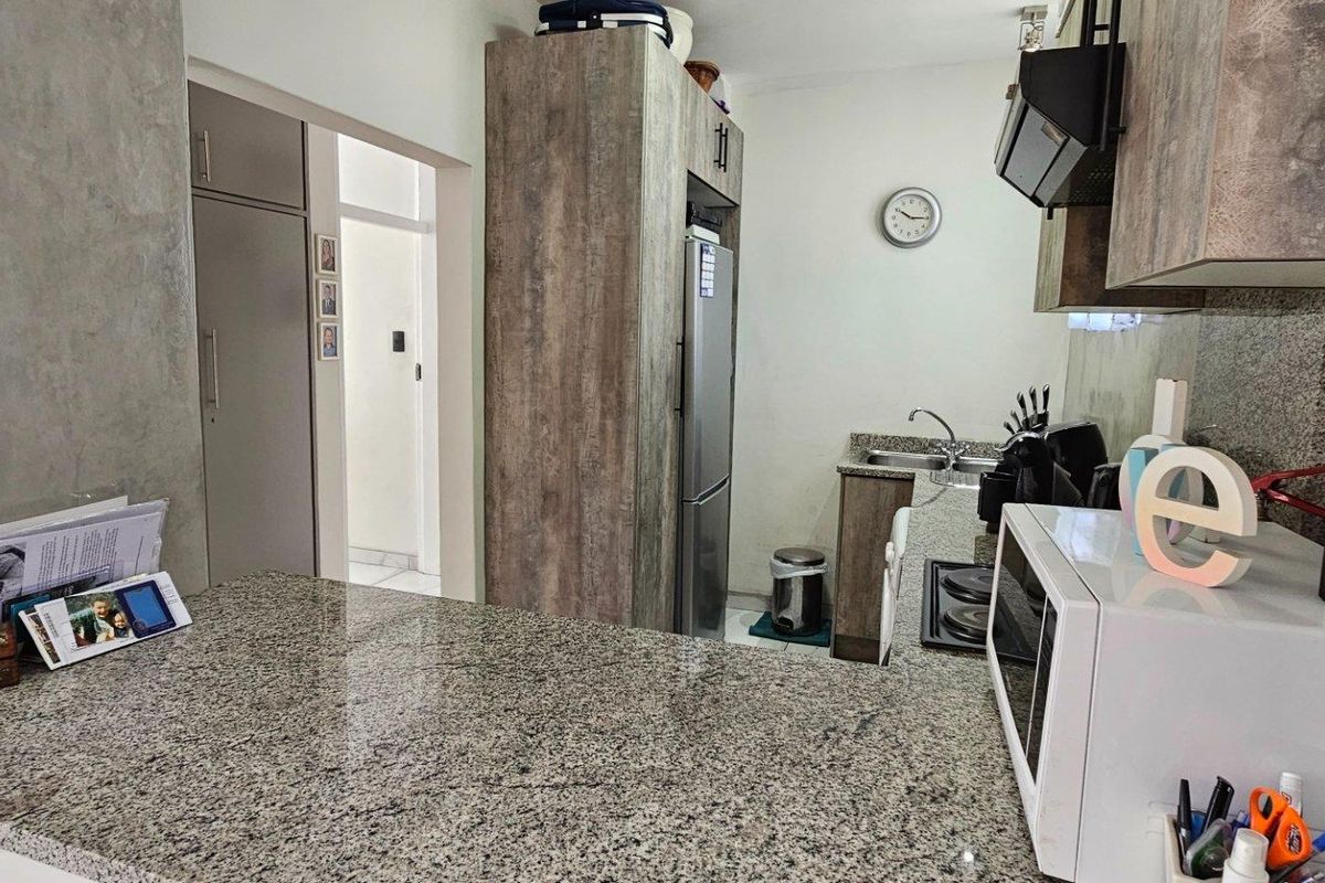 A functional kitchen featuring granite countertops, built-in cabinetry, and a breakfast bar area, providing a practical layout for daily meal preparation.