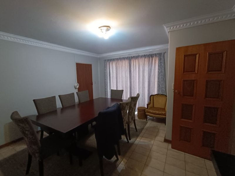 A dining room featuring tiled flooring, crown molding, and a sliding glass door providing access to the exterior.