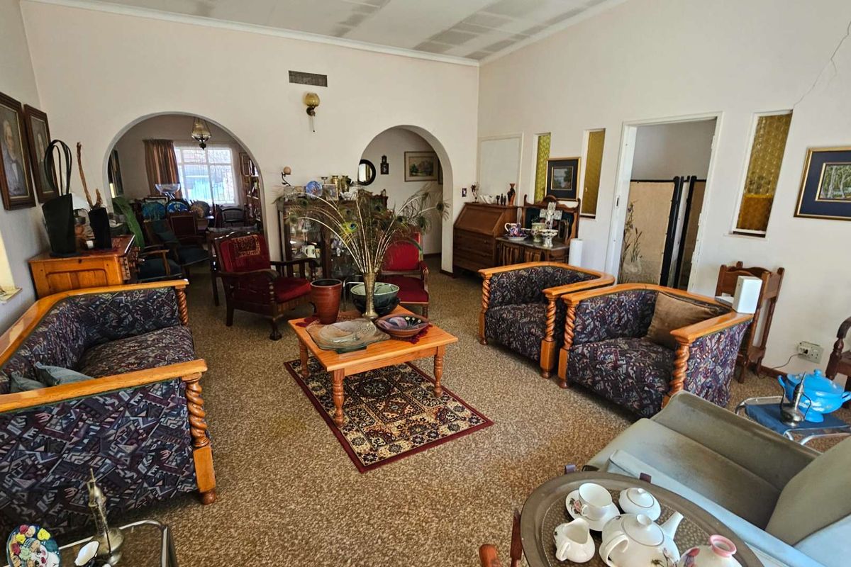 Spacious living room featuring arched doorways, textured ceiling, and carpeted flooring, offering a traditional layout with multiple access points to adjacent rooms.