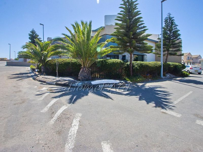 A street-level view of the property frontage, featuring paved road access, street lighting, and established landscaping along the verge.
