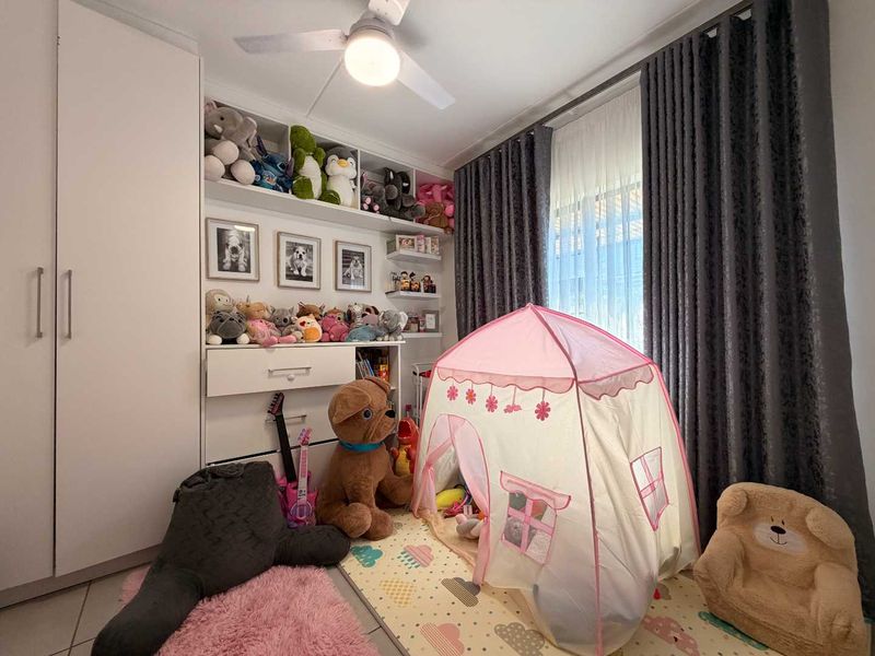 A well-maintained bedroom featuring built-in cabinetry, integrated shelving, a ceiling fan, and tiled flooring.