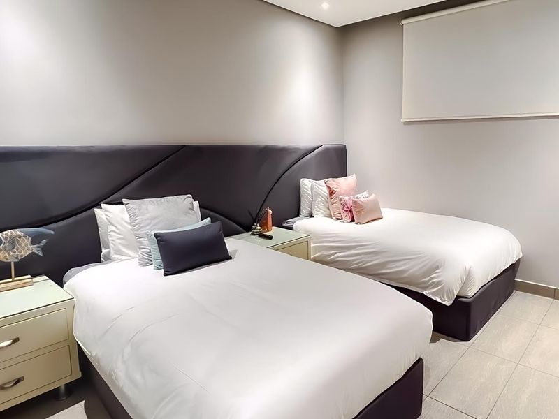 A well-maintained bedroom featuring neutral wall tones, tiled flooring, a modern roller blind, and recessed ceiling lighting.
