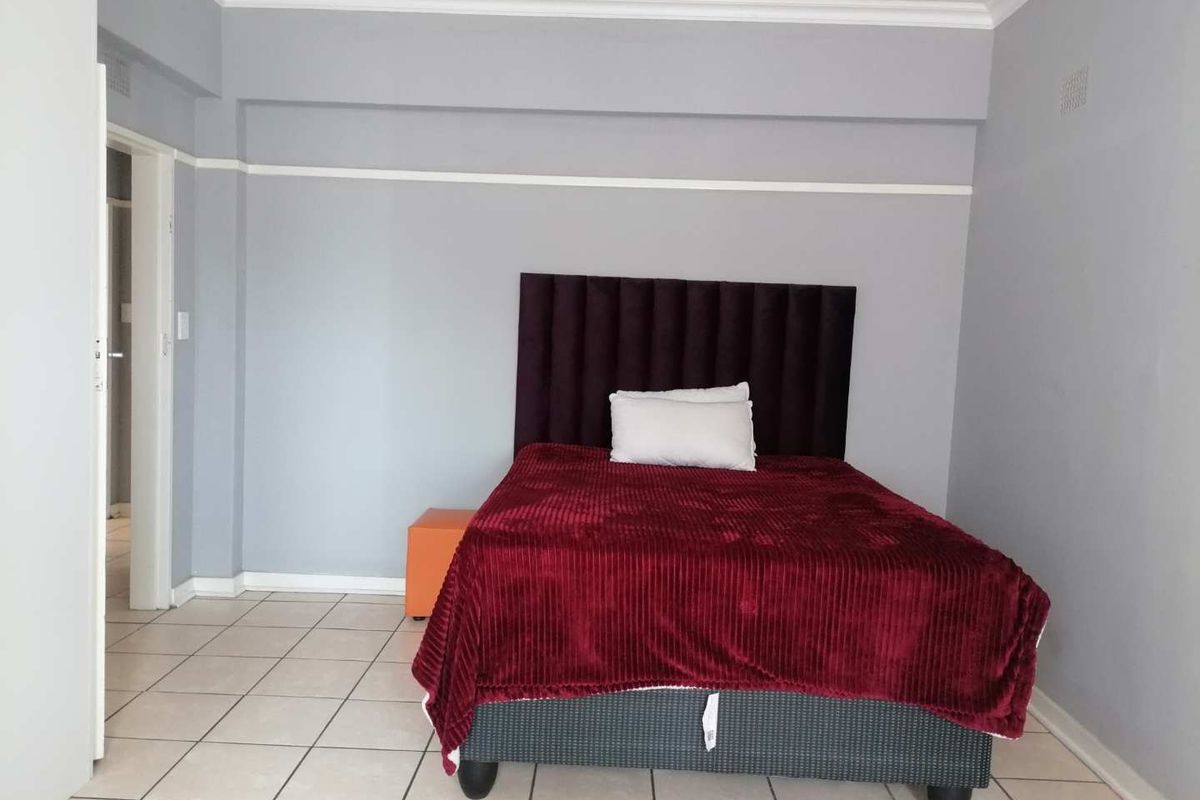 A bedroom featuring tiled flooring, crown molding, and a neutral wall finish, providing a clean and functional living space.