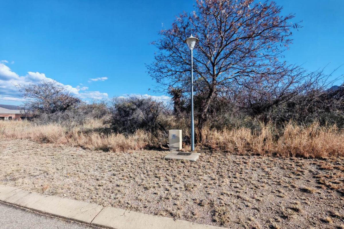 A view of the vacant residential land showing the street curb, a utility box, and a street light pole.