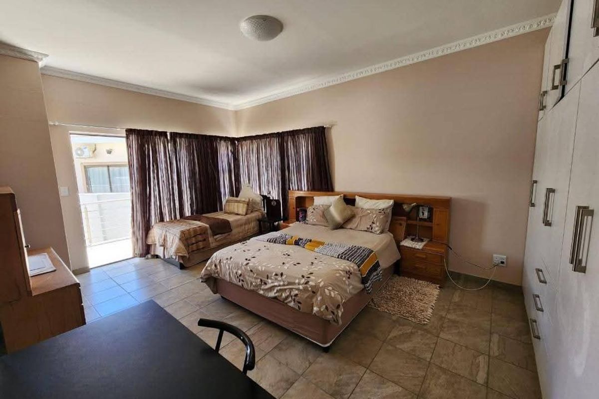 Spacious bedroom featuring built-in cupboards, tiled flooring, and direct access to a private balcony through sliding doors.