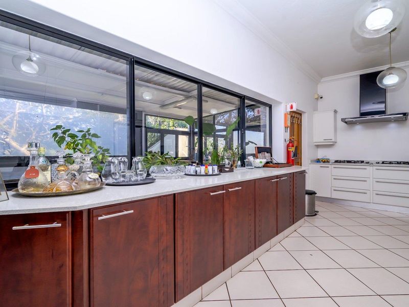 Spacious kitchen featuring dark wood cabinetry, stone countertops, a gas hob with extractor fan, and large windows overlooking the outdoor area.