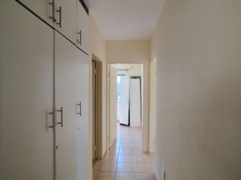 A functional hallway featuring tiled flooring and extensive built-in cupboard storage, providing efficient access to adjacent rooms.