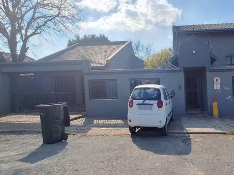 Front elevation of a residential property featuring a tiled roof, security bars on windows, and a paved driveway entrance.