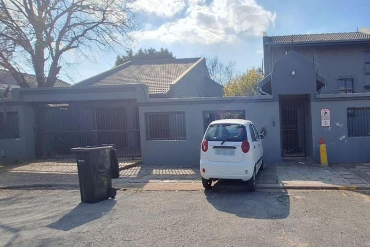 Front elevation of a residential property featuring a tiled roof, security bars on windows, and a paved driveway entrance.