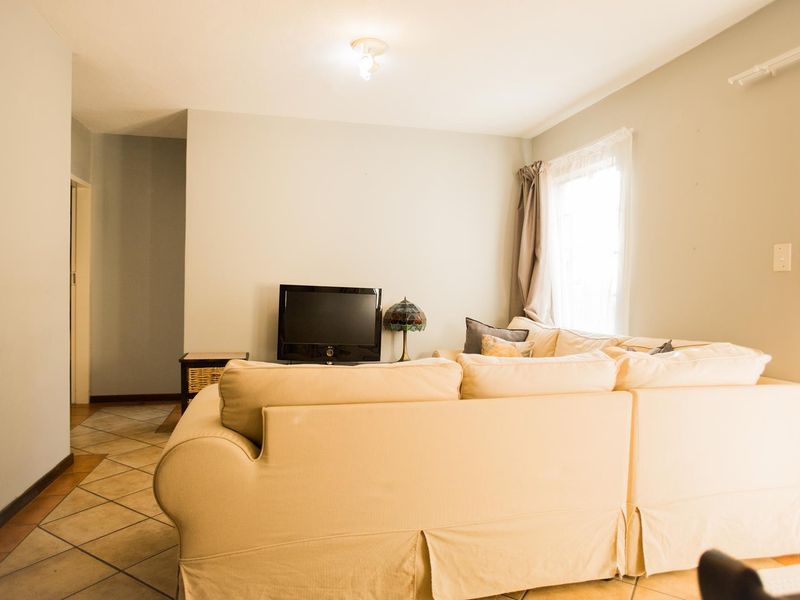A functional living room featuring tiled flooring and neutral wall finishes, providing a comfortable and versatile space for relaxation.