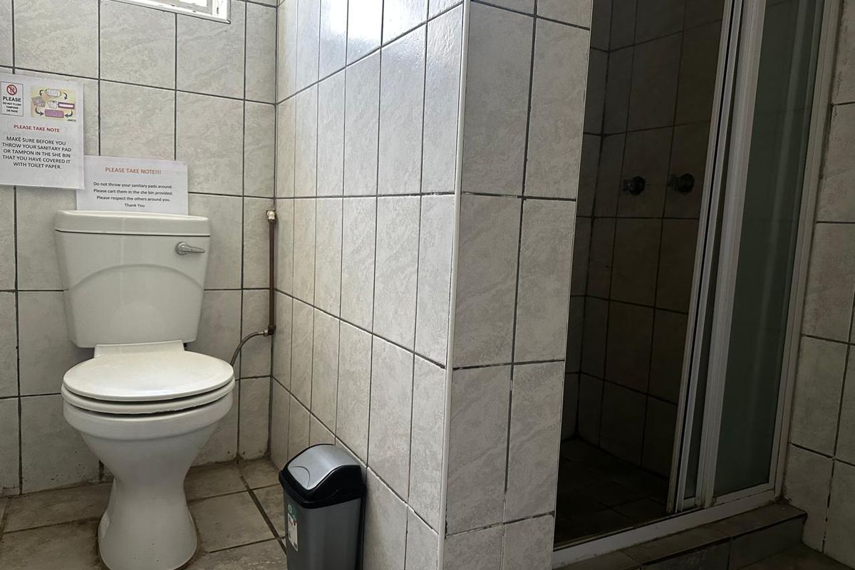 A functional bathroom featuring a standard toilet and a tiled shower enclosure with a glass door.