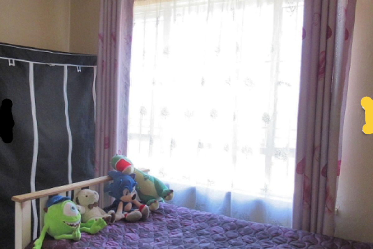 A bedroom featuring a large window with curtains, providing natural light to the space.