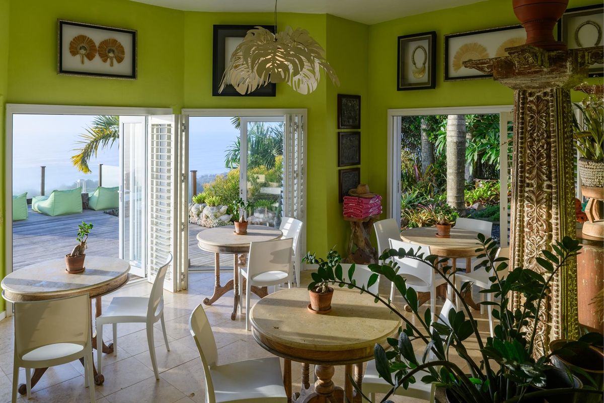 Bright living area featuring lime green walls, tiled flooring, and large bi-fold doors opening onto an outdoor deck with scenic views.